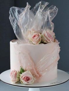 a wedding cake decorated with pink roses and veils