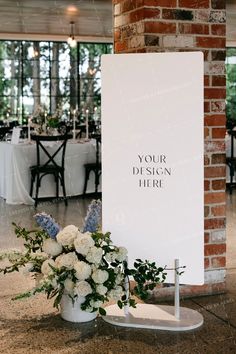 a white sign sitting on top of a table next to a vase filled with flowers