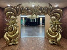 an entrance decorated with gold balloons and flowers in the middle of a hallway that leads to a hall