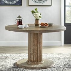 a round table with two vases on it in front of pictures and paintings above