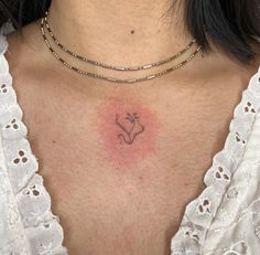 a close up of a woman's chest with a small tattoo on her chest