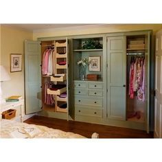 an open closet in a bedroom with clothes hanging on the walls and drawers below it