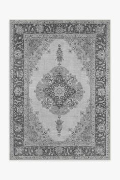 a gray rug with an ornate design on the center and sides, in black and white