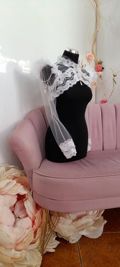 a mannequin is sitting on a pink couch with a veil draped over it