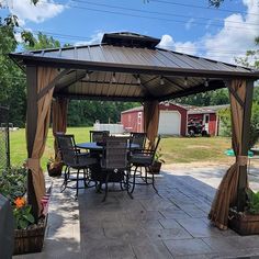 an outdoor patio with a table and chairs under a gazebo in the middle of a yard