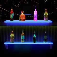 there are many bottles on the shelf in the bar with blue lights behind them,