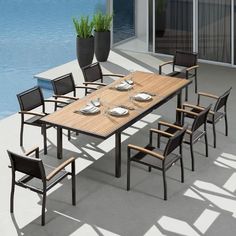 an outdoor dining table with six chairs next to a swimming pool and planter filled with water