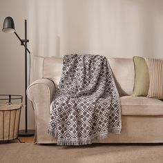 a couch with a blanket on it next to a lamp