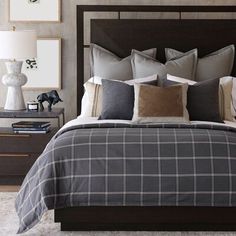 a bed with grey and white plaid comforter in a bedroom next to two nightstands