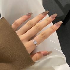 a woman's hand with a ring on it and some manicured nails in front of her