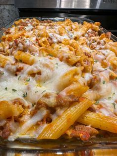 a glass casserole dish filled with pasta and meat covered in sauces, cheese and parmesan