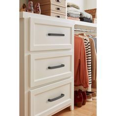 a white dresser sitting next to a closet filled with clothes and shoes on top of it