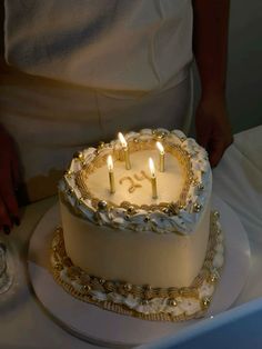 a white cake with three lit candles on it