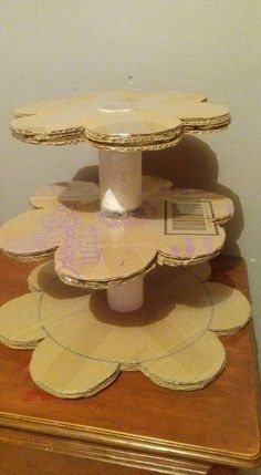 a three tiered cake stand on top of a wooden table next to a wall