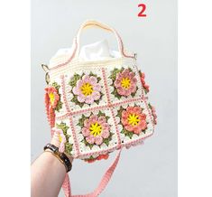 a crocheted bag with flowers on the front and side, attached to a handbag