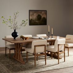 a dining room table with chairs and a vase on the table in front of it