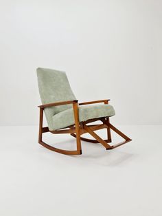 a wooden rocking chair with a light green upholstered seat and backrest, against a white background