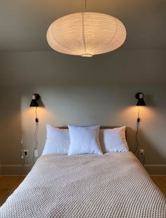 a bed with two lamps on either side of the headboard and one light above it