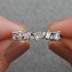 someone is holding their wedding ring with three stones on each side and four diamonds in the middle