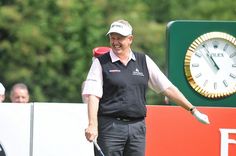 a man holding a golf club in front of a clock