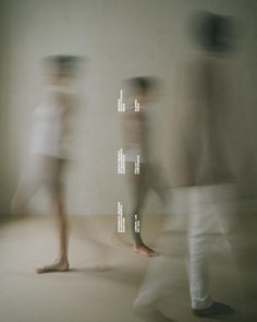 blurry photograph of three people walking in front of a wall with words on it