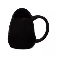 a black coffee mug sitting on top of a white table next to a cup holder