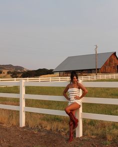 a woman is leaning on a white fence