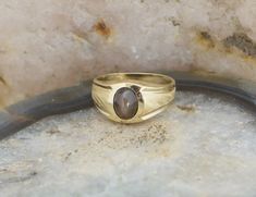 This is a 10K Synthetic Star Sapphire Ring, light brown 5x8mm oval, high dome stone, florentine finish to center of top high polished edges. shank 3/8 inch across, Ring size 7.75, weight 4.1 grams Stock # BB104R16 This listing contains photographs of the actual item you will receive. Our items are in excellent condition with little or no signs of wear and many are one of a kind pre-owned estate finds. Please look closely at the pictures in this listing as they are part of the product description Formal Oval Cabochon Moonstone Ring, Classic Brown Oval Ring, Classic Oval Brown Ring, Classic Gold Moonstone Ring With Oval Cabochon, Oval Gemstone Ring For Memorial, Heirloom Oval Moonstone Ring With Polished Finish, Brown Oval Jewelry For Anniversary, Oval Brown Jewelry For Anniversary, Brown Oval Gemstone Rings