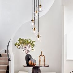 a table with two vases on it and some lights hanging from the ceiling above