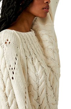 a woman wearing a white cable knit sweater