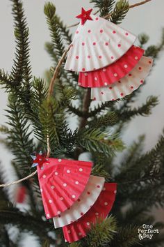 three paper christmas trees hanging from a tree branch with red and white polka dots on them