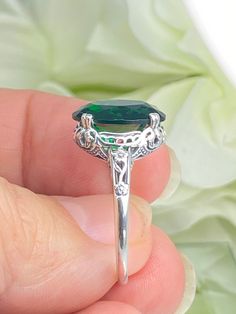 6ct. Simulated Emerald 925 Sterling Silver RingEdward Design#D70 This filigree ring is a reproduction of a sterling silver Edwardian antique with a simulated green emerald gemstone solitaire. This full cut oval gem is 14mm x 10mm. This ring sits 7mm off the finger. The inside of the band is marked 925 for sterling silver. Notice the beautiful leaf and floral design of the silver filigree setting and etched band. This ring is part of our Edward series, which includes bracelets, earring, and pendant necklaces. This is the original Edward design, with a generously cut gemstone that is accented above the filigree. This is a lovely rendition of an antique filigree ring. This amazing design is pure style and grace. You can dress it up or down, it's the perfect statement. Your every movement will Classic Green Emerald Ring For Collectors, Elegant Silver Emerald Ring Collectible, Classic Silver Emerald Ring With Accent Stones, Classic Sterling Silver Emerald Ring With Accent Stones, Classic Emerald Ring With Accent Stones In Sterling Silver, Green Sterling Silver Filigree Ring For Anniversary, Classic Green Filigree Ring With Gemstone, Antique Silver Emerald-cut Emerald Ring, Classic Green Sterling Silver Filigree Ring