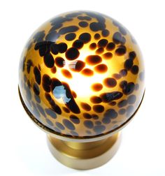 a close up of a glass object on a white surface with black dots and gold trim