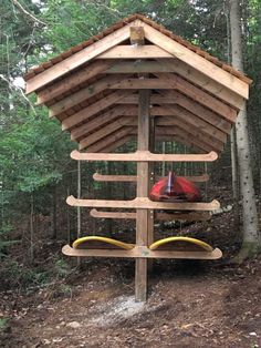 a wooden structure in the woods with kayaks on it's sides and trees around