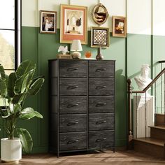 a living room with green walls and pictures on the wall next to a black dresser