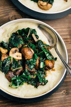 two plates filled with mashed potatoes and spinach on top of a wooden table