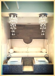 a living room with couches and chandeliers hanging from the ceiling above them