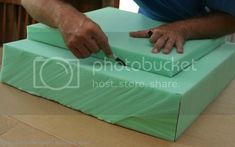 a person cutting into a green box with a knife on it's side,