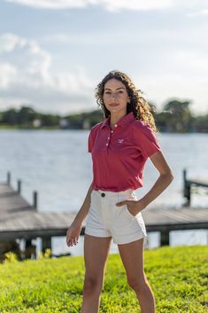 a woman standing on top of a lush green field next to a body of water