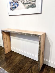 a wooden bench sitting on top of a hard wood floor next to a white wall