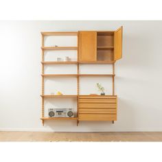 a wooden shelf with drawers and shelves on the wall next to a white wall in an empty room