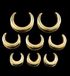 six pairs of gold plated metal rings on a black background