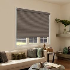 a living room filled with furniture and a window covered in roman blind shades on the windowsill