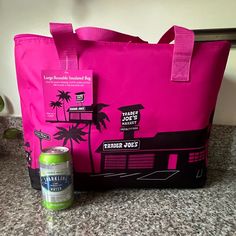 a pink tote bag sitting on top of a counter next to a can of beer