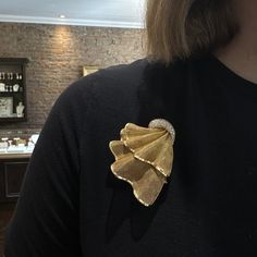 a woman wearing a black shirt with a gold brooch