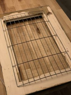 an old window frame with wire on the bottom and wood in the middle, sitting on top of a hard wood floor