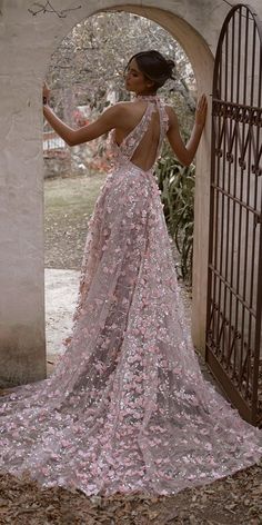 a woman standing in front of an archway wearing a dress with pink flowers on it