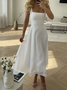 a woman in a white dress taking a selfie