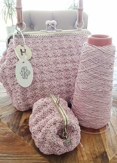 two crocheted bags sitting on top of a wooden table next to a spool of yarn