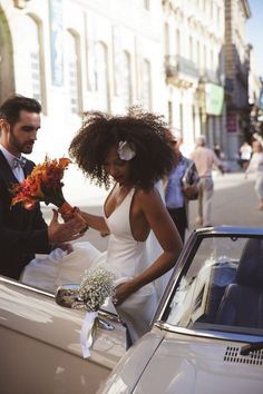 a man and woman standing next to a car